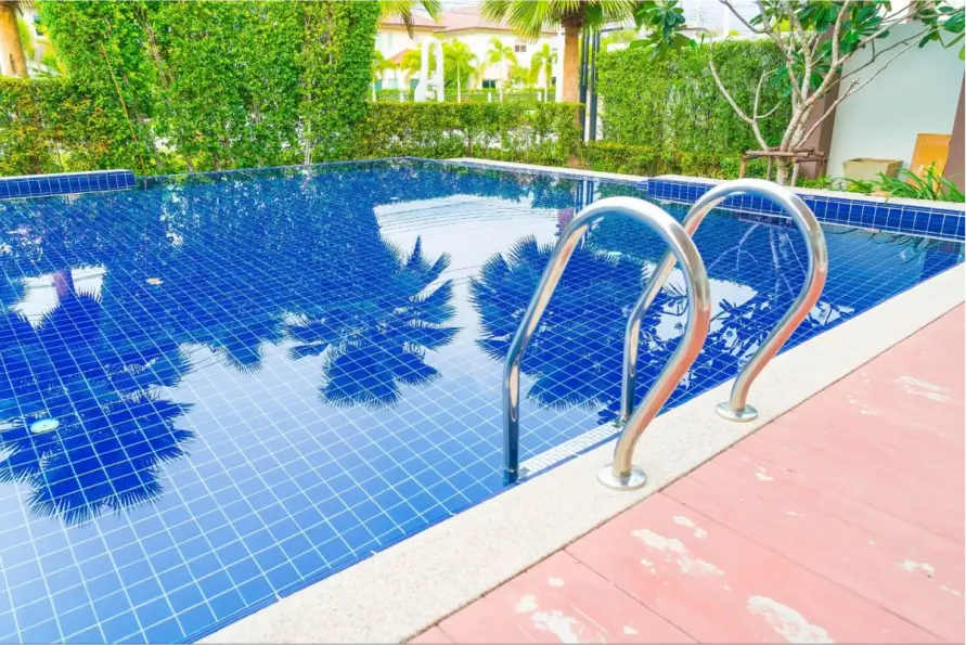 Blue-tiled pool with lush green surroundings