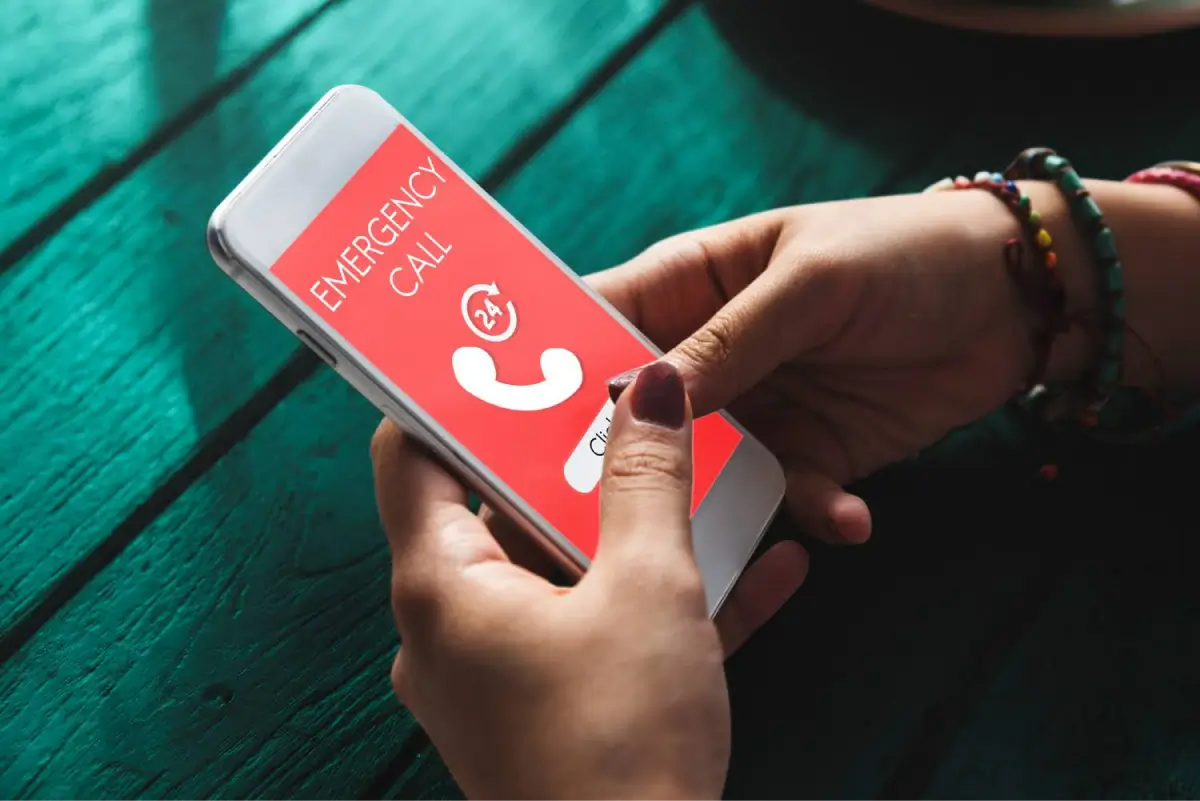 Person holding a smartphone displaying an emergency call screen.