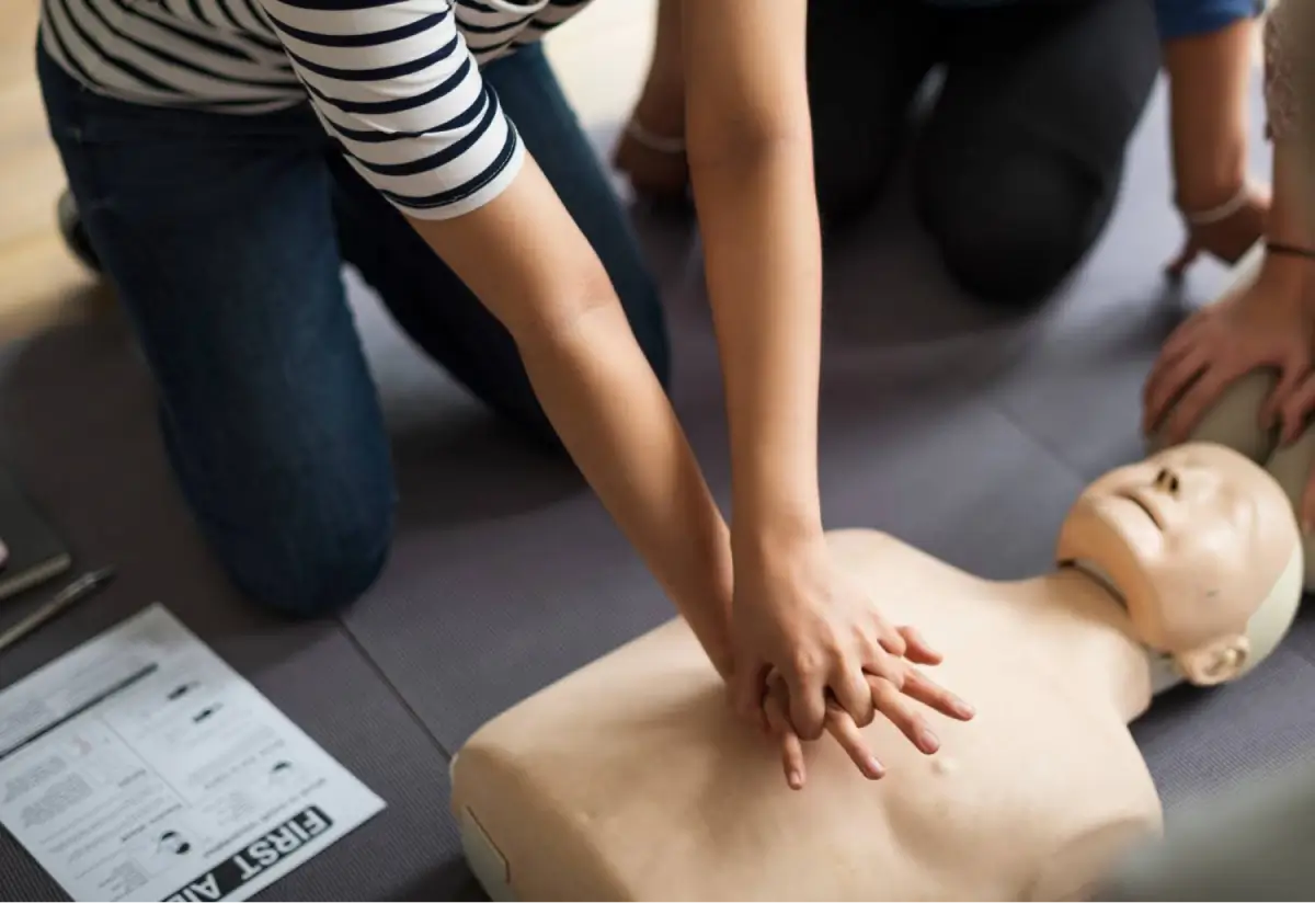 Individual performing CPR on a practice dummy during a first-aid training session.