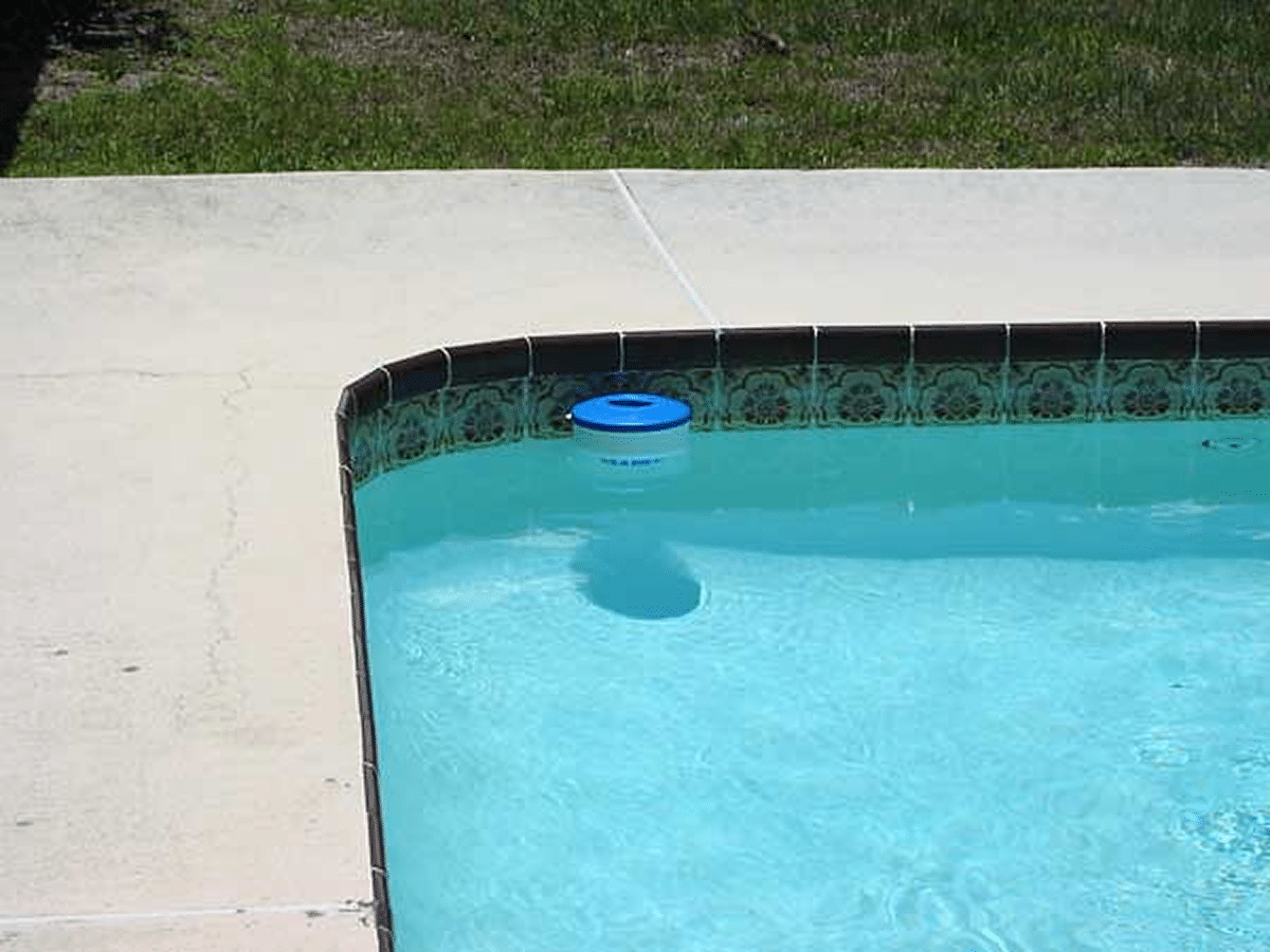 Close-up of a swimming pool with a floating blue chlorinator near the edge.