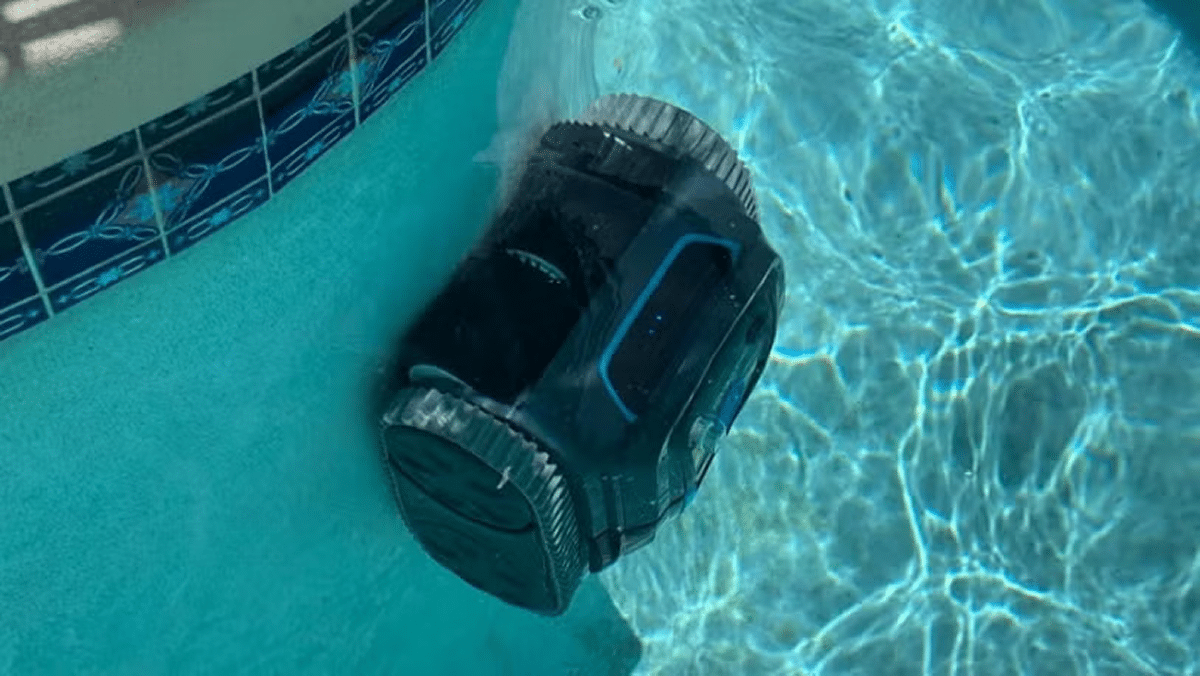 A robotic pool cleaner underwater, scrubbing the pool walls.